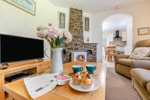 A living room with a TV, a stone fireplace, a dining area, and a cozy sofa.