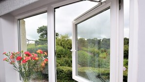 A window with a view of a garden and a vase with flowers on the window sill. - 2 Bed in Tiverton (oc-shayn) (Shillingford)