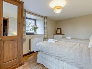 A bedroom with two beds, a wooden wardrobe, a bedside table with a mirror, and a window with curtains. - 2 Bed in Beaworthy (oc-tilli) (Virginstowe)