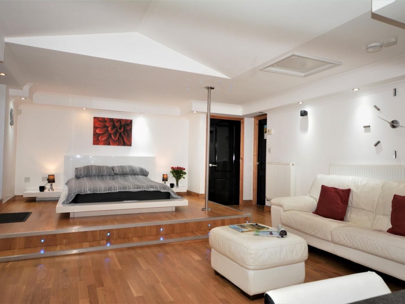 Une chambre à coucher moderne avec un lit, un canapé blanc, une table basse et une grande fenêtre.