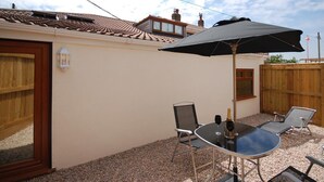 Eine Terrasse mit Tisch, Stühlen und einem großen Sonnenschirm.