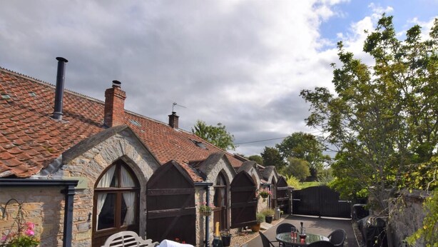 Un bâtiment en pierre avec un toit en tuiles, un jacuzzi et un espace salon extérieur.