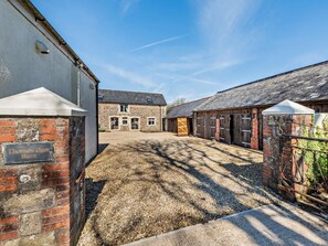A stone building with a gravel driveway and a brick wall with a sign. - 6 Bed in Bideford (oc-thorn) (Buckland Brewer)