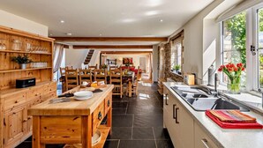 A spacious kitchen with a dining area, wooden cabinetry, and a large window with a view. - 6 Bed in Bideford (oc-thorn) (Buckland Brewer)