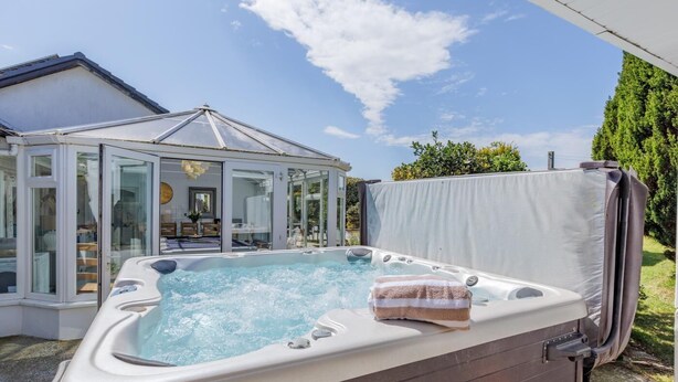 Ein Whirlpool mit Handtuch, einer gläsernen Struktur und einem Haus im Hintergrund.