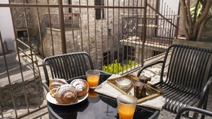 A table with pastries, juice, and a tray on a balcony with chairs.