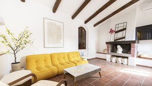 A living room with a yellow sofa, a white coffee table, a fireplace, and a potted plant.