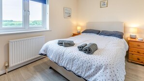Une chambre à coucher avec un lit, deux tables de chevet, une fenêtre et un radiateur.