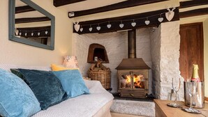 Ein gemütliches Zimmer mit einer Couch, einem Kamin, einem Spiegel und einem Holztisch mit Gläsern und einer Flasche.