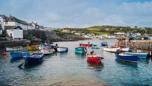 Un puerto con barcos amarrados, muros de piedra y edificios al fondo.