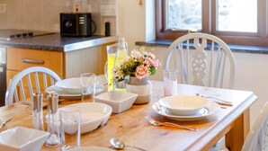 Una mesa de comedor dispuesta con platos, vasos y cubiertos, un florero con flores y una botella de agua.