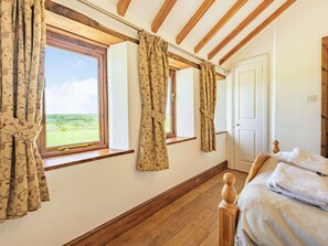A bedroom with wooden beams, a bed, a window with curtains, and a door. - 5 Bed in Okehampton (oc-wagol) (Lewdown)