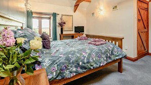 Een slaapkamer met een bed, een bureau, een televisie en een houten plafond.
