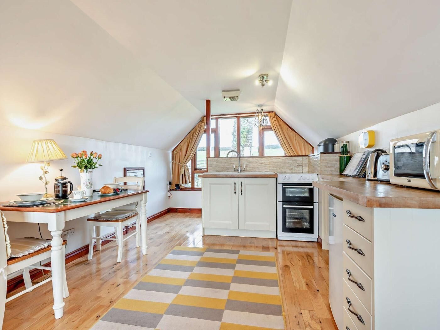 A cozy kitchen with a wooden table, a coffee maker, and a toaster.