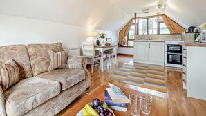 A cozy loft with a sofa, dining table, and kitchenette. - 1 Bed in Looe (oc-couvw) (Lansallos)