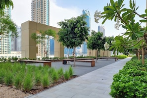 A landscaped urban area with a paved walkway, benches, and greenery. - Gogoto7 Luxe 2BR Burj Khalifa View Prime Location (Dubai)