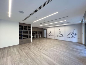 A spacious room with a wooden floor, built-in shelving, and wall-mounted exercise equipment. - Gogoto7 Luxe 2BR Burj Khalifa View Prime Location (Dubai)