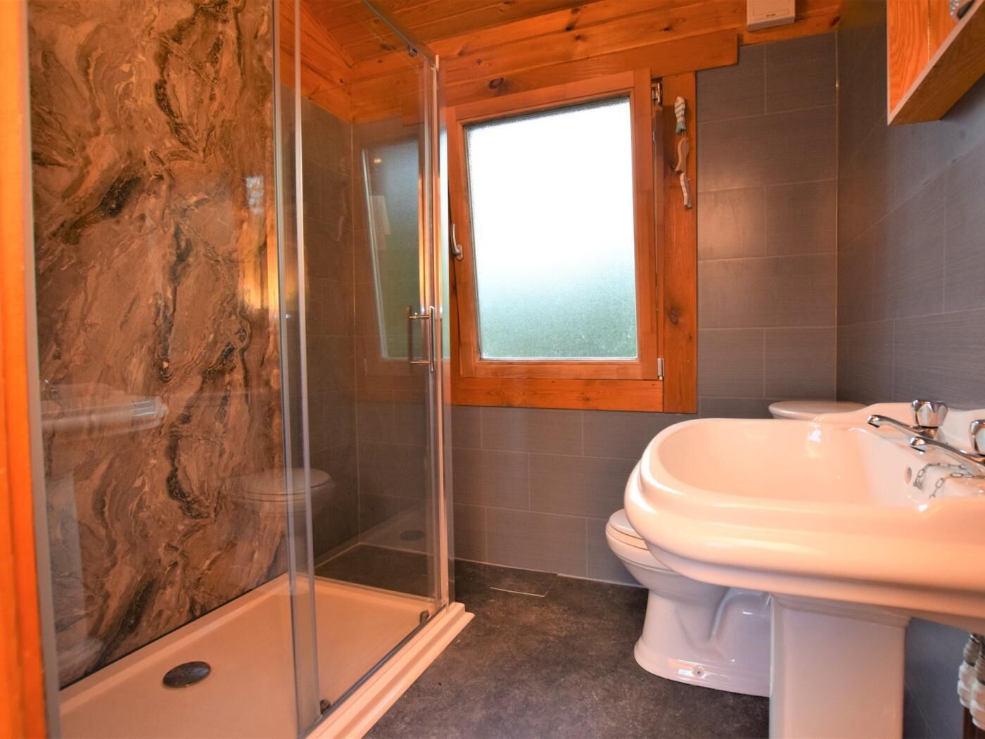 Une salle de bain avec une douche à parois de verre, des toilettes et un lavabo.