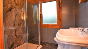 Une salle de bain avec une douche à parois de verre, des toilettes et un lavabo.