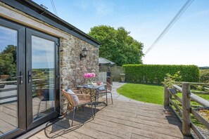 Eine Terrasse mit Tisch und Stühlen, eine Steinsäule und ein Holzzaun.