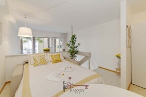 A hotel room with a bed, bedside table, lamp, window, and a potted plant. - Garden Apartment in Center - Ambra (Lugano)
