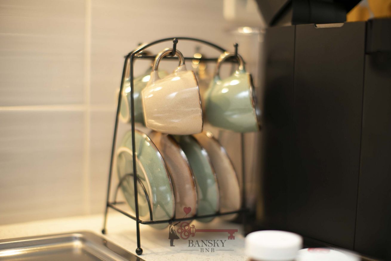 Una cocina con una estantería metálica que contiene varios tazas de cerámica.