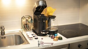Ett kök med en kaffebryggare, en vattenkokare, en glaskanna och en kaffekvarn på bänkskivan.