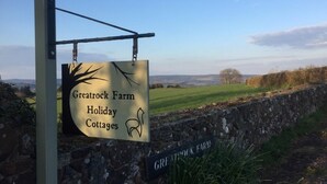 Un cartel de Greatrock Farm Holiday Cottages con vistas al campo.