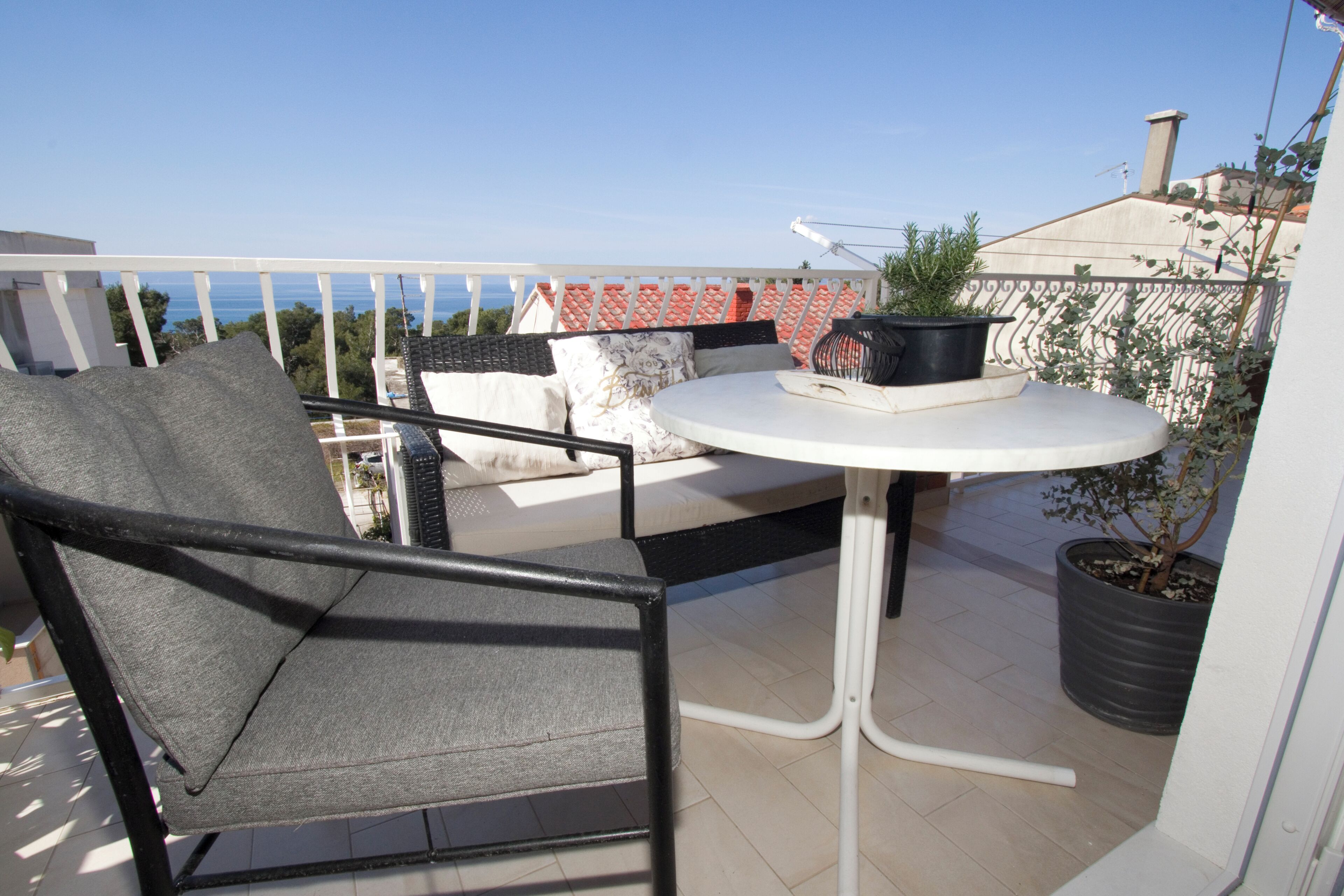 A balcony with a round table, a chair, and potted plants.