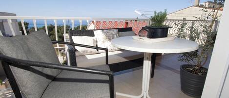 A balcony with a round table, a chair, and potted plants.