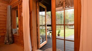 Une cabane en bois dotée d’une porte-fenêtre coulissante qui donne sur un patio extérieur avec une table et des chaises.