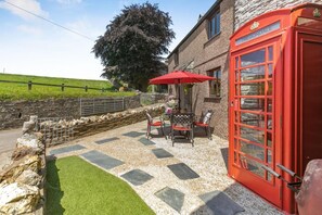 A red telephone booth, outdoor seating with chairs and a table, and a stone wall. - 2 Bed in Liskeard (oc-04708) (Menheniot)