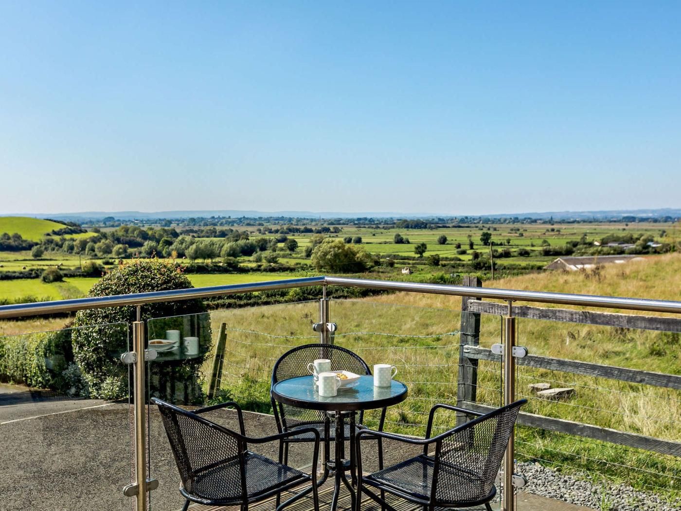 Balcón con mesa y sillas con vistas a un paisaje rural.