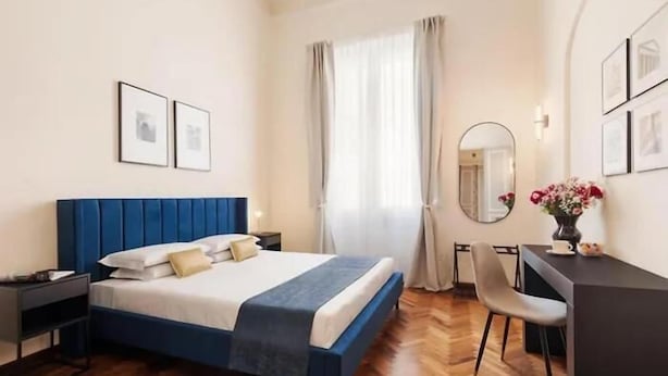 A bedroom with a bed, bedside tables, a desk, a chair, and a mirror.