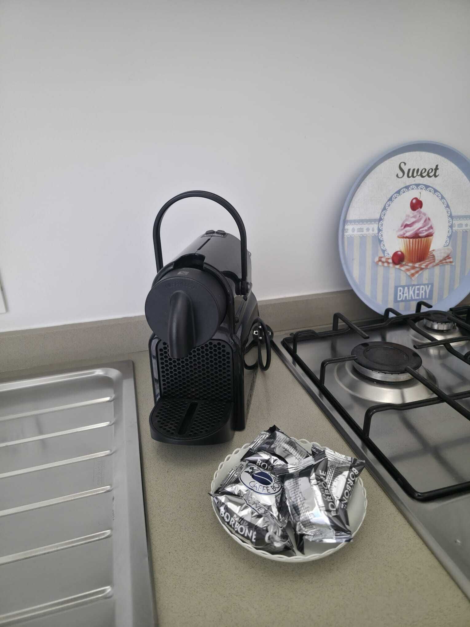 A kitchen with a portable gas stove, a kettle, and a plate of packaged food.
