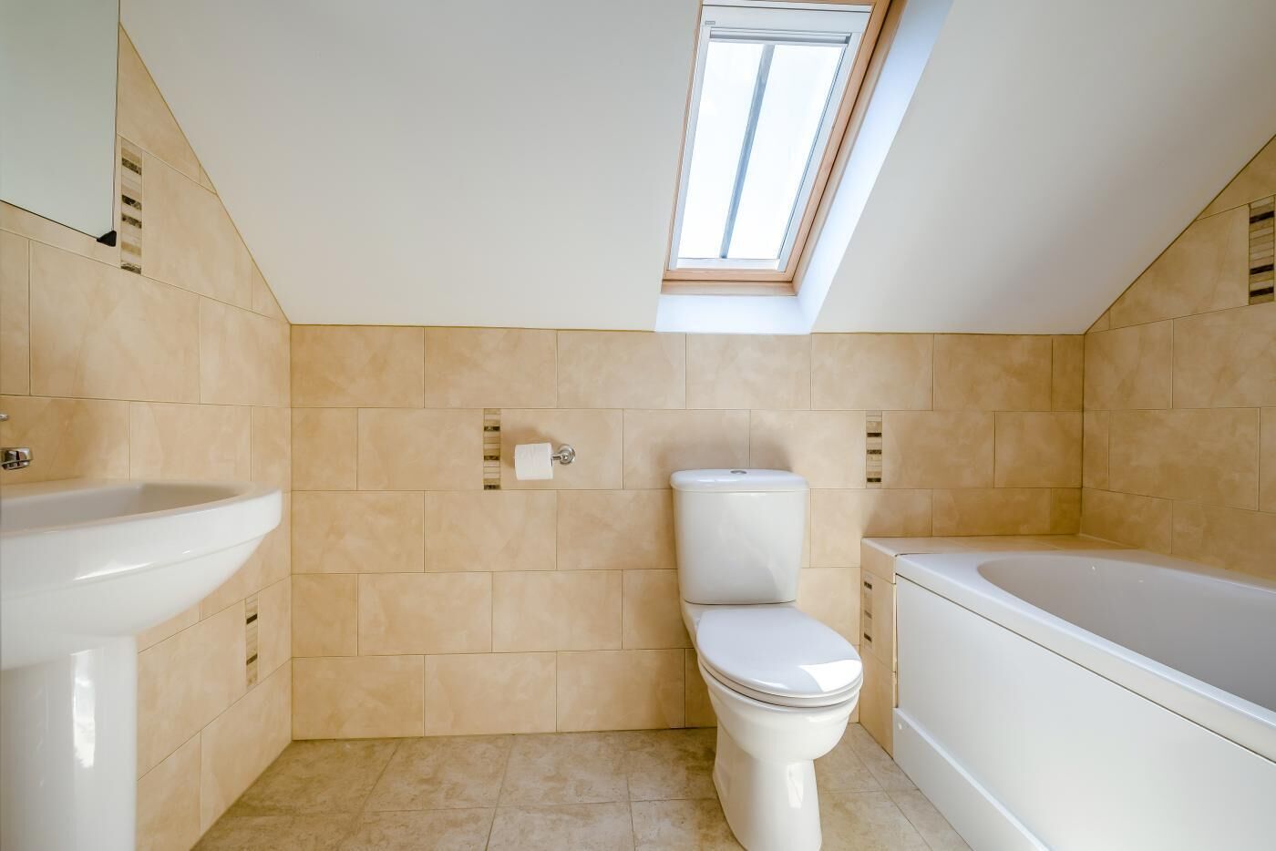 A bathroom with a skylight, a toilet, a sink, and a bathtub.