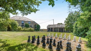 A chessboard set up outdoors with a stone building in the background. - 3 Bed in Bude (oc-woott) (Poundstock)