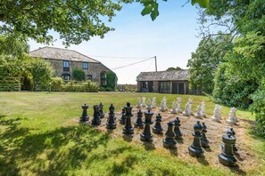 A chessboard set up outdoors with a stone building in the background. - 3 Bed in Bude (oc-woott) (Poundstock)