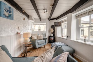 A cozy room with a fireplace, a sofa, a lamp, and a view of the street.