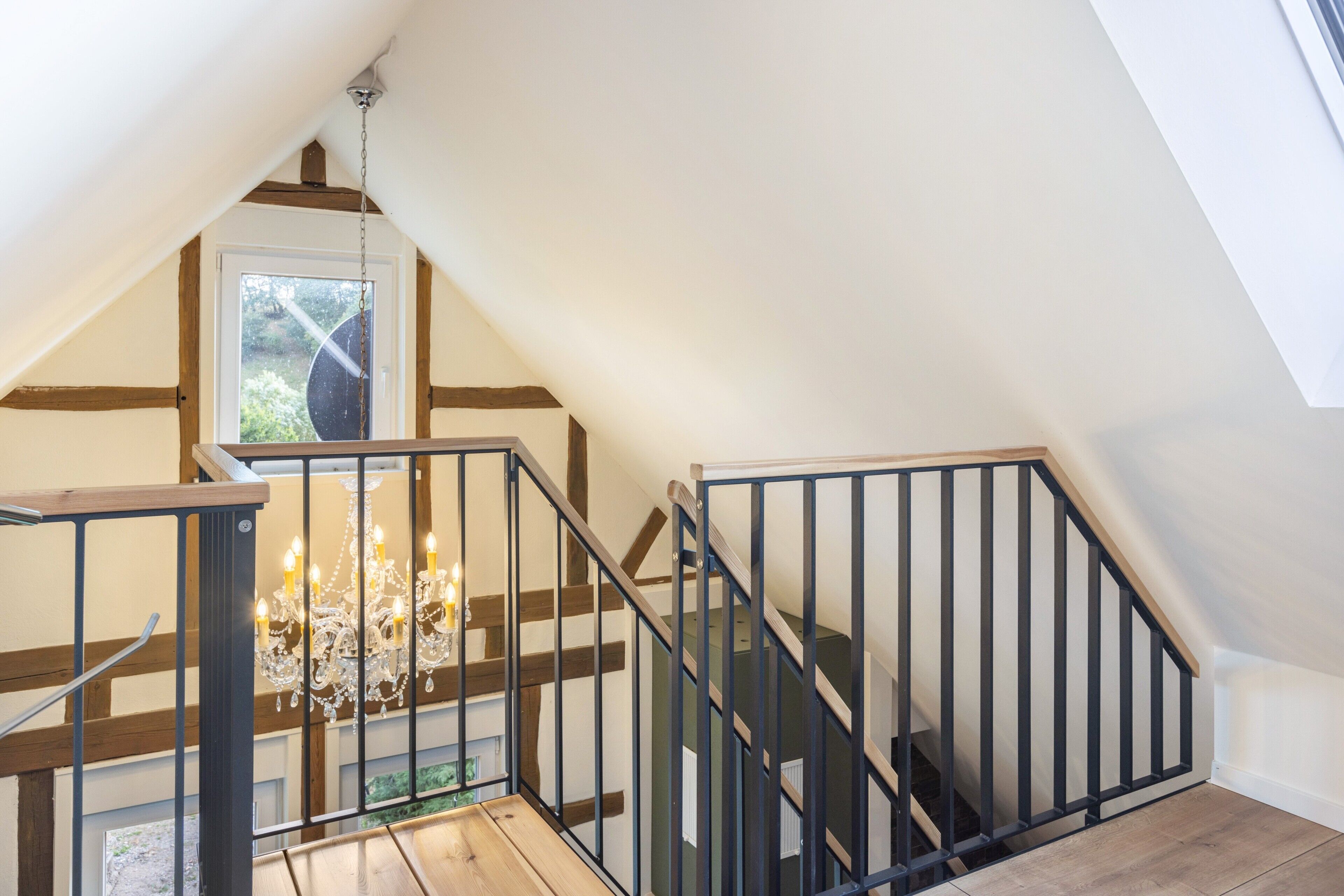 A wooden staircase with a black railing leading to a landing.