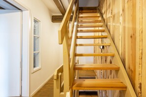 Una escalera de madera con barandilla que lleva a un piso superior.