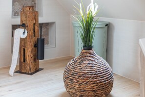 A room with a woven basket vase on a wooden floor, a wooden sculpture, and a green cabinet. - Apartment "Mühlenapartment" with Shared Garden and Wi-Fi (Kirtorf)