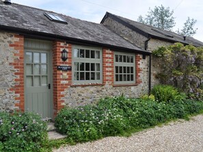 A stone building with a green door, a sign reading 'Bloomsbury Loft,' and a window with shutters. - 2 Bed in Axminster (oc-blolo) (Axminster)