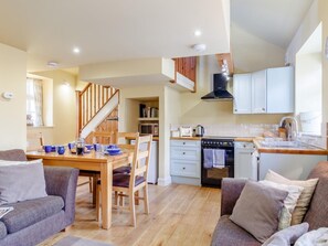 A cozy living room with a dining area, wooden flooring, and a kitchen with white cabinets and a black range hood. - 2 Bed in Axminster (oc-blolo) (Axminster)
