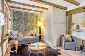 Un salon chaleureux avec un canapé gris, une table basse ronde en bois, une lampe et un mur décoratif.