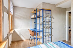 A compact bedroom with a bed, a desk, and a chair.