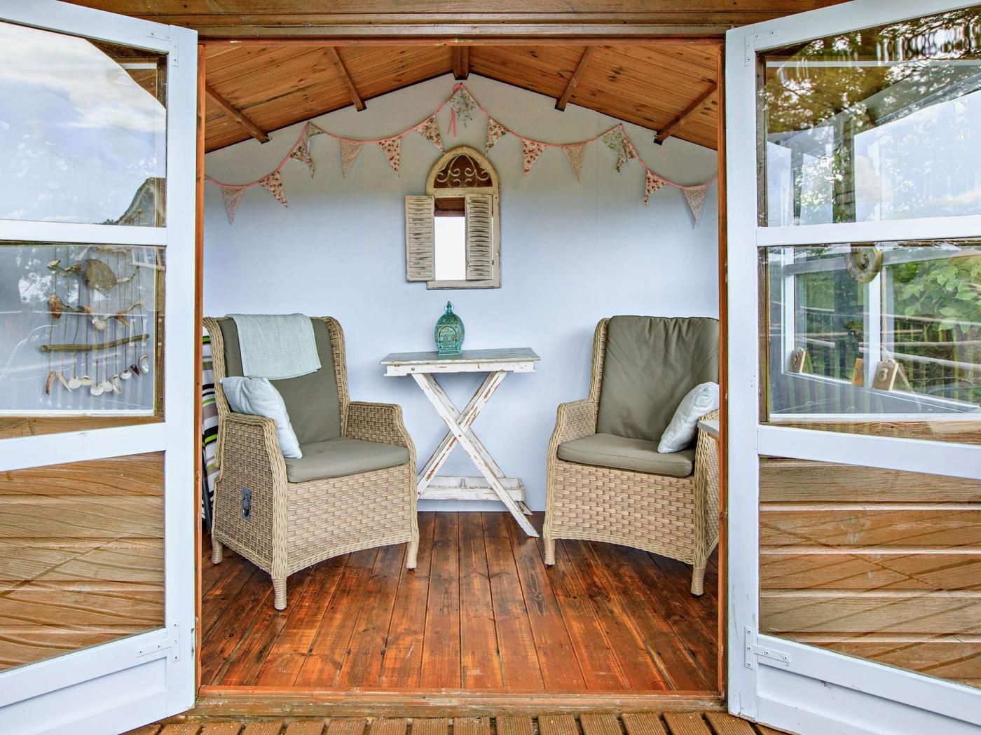 A cozy room with two wicker chairs, a small table, and a decorative mirror on the wall.