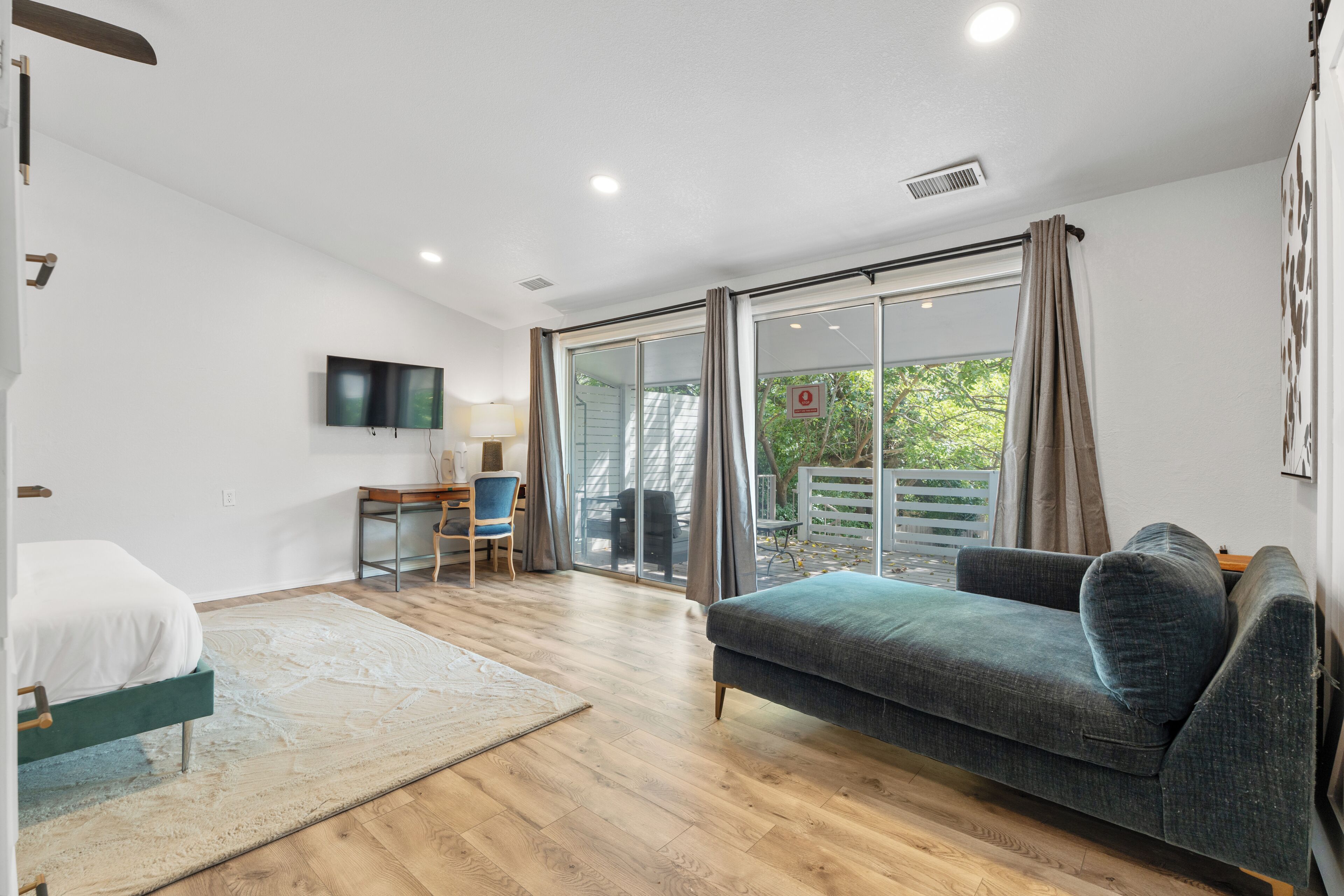 Quarto moderno com cama, sofá, escrivaninha e televisão.