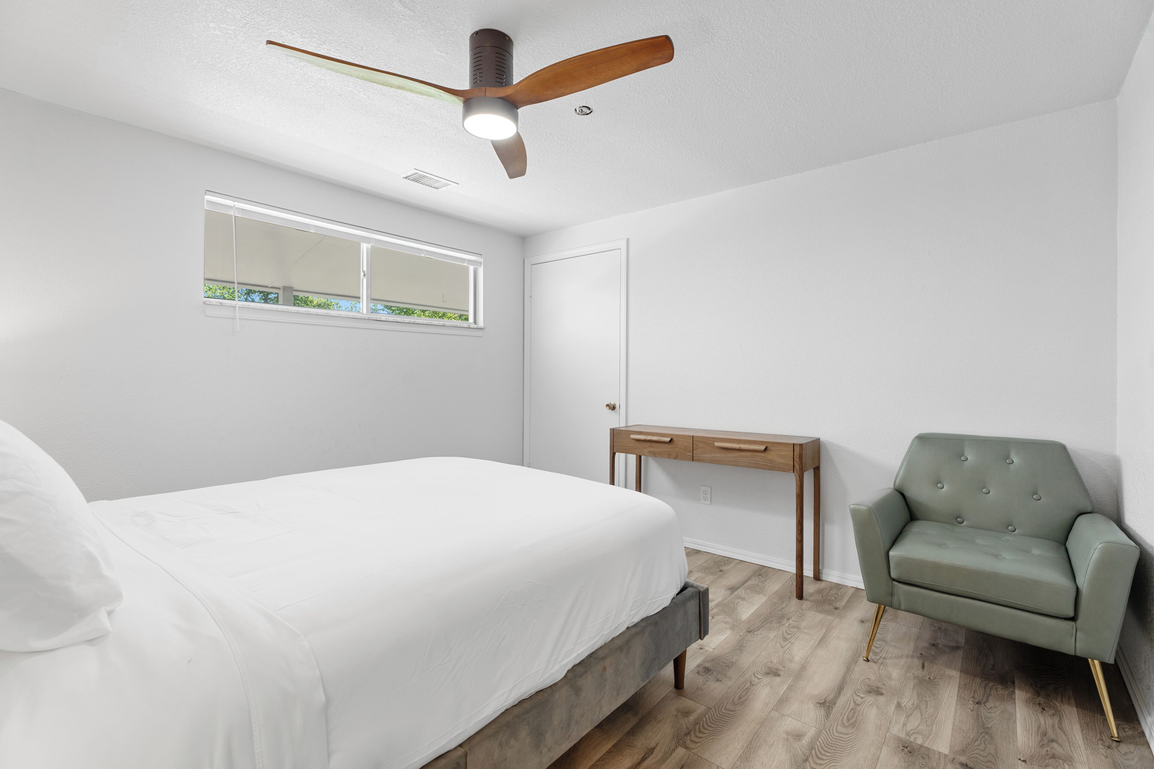 Une chambre à coucher comprenant un lit, un bureau, une chaise et un ventilateur de plafond.