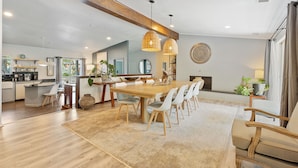 Un comedor amplio con una mesa y sillas de madera, un tapete grande e iluminación colgante.